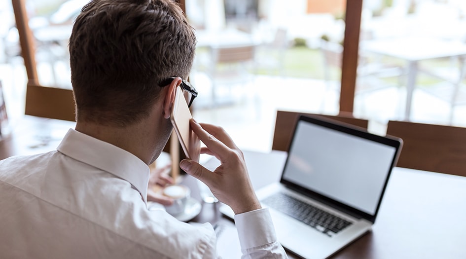 A man talks on his cellphone and looks at his laptop, while he learns what high risk insurance is and who needs it