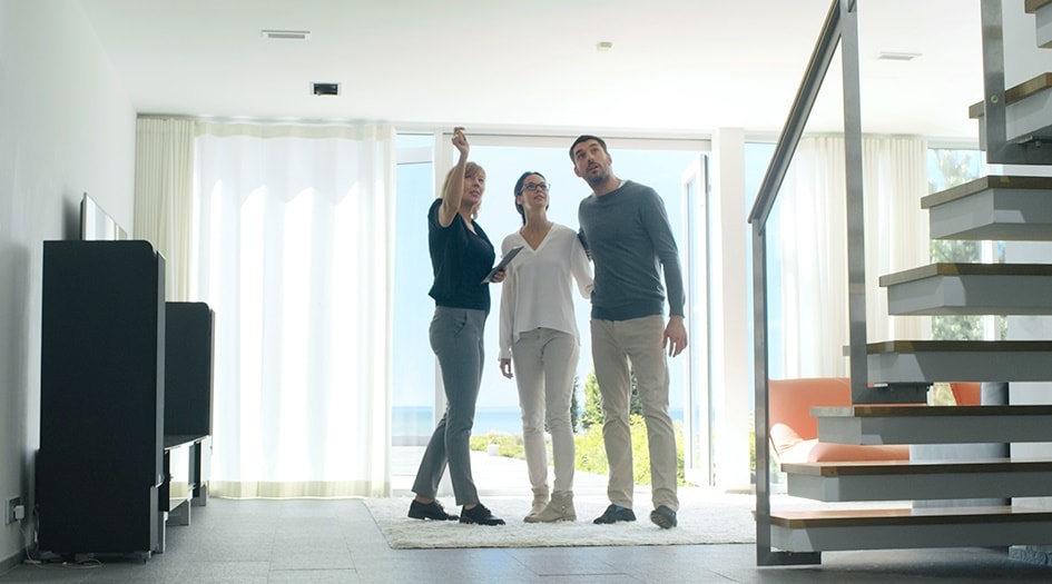 Trois personnes debout dans un salon, cherchant un appartement à louer.