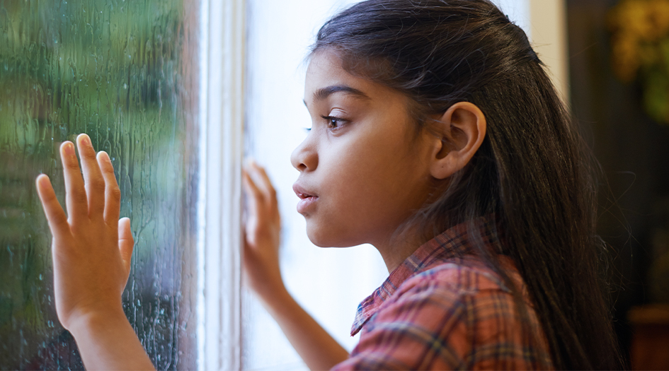 Un enfant regarde la pluie tomber, illustrant un événement lié aux rivières atmosphériques, bombes cycloniques et déréchos.