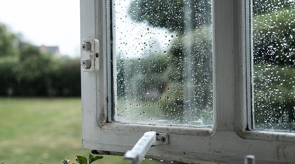 Rain drops sit on an open window, showing why you should know if your home insurance includes water damage coverage