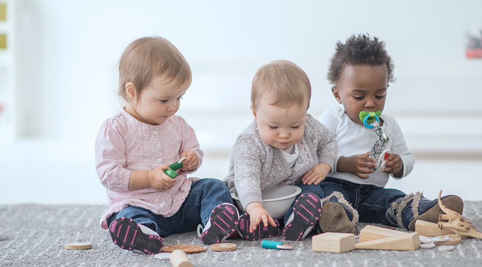 Ouvrir une garderie en milieu familial nécessite différentes assurances, comme le démontrent trois jeunes enfants qui jouent par terre.