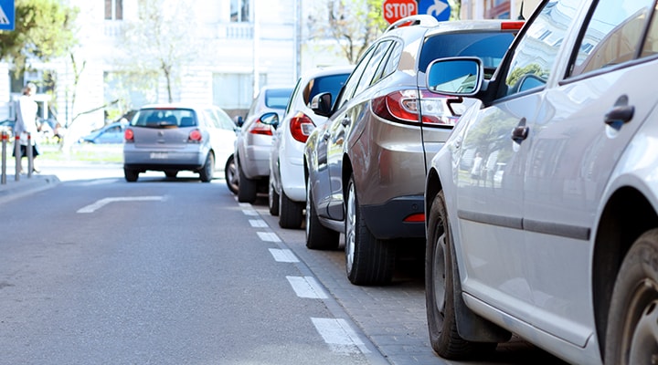 Advanced driver assist systems can help make parking easier, like parallel parking, as shown by a row of cars parked at the side of the road