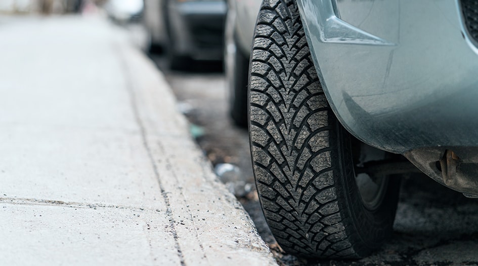 A car's tires are pointed towards the curb, showing one of the most forgotten driving rules when parking on a hill