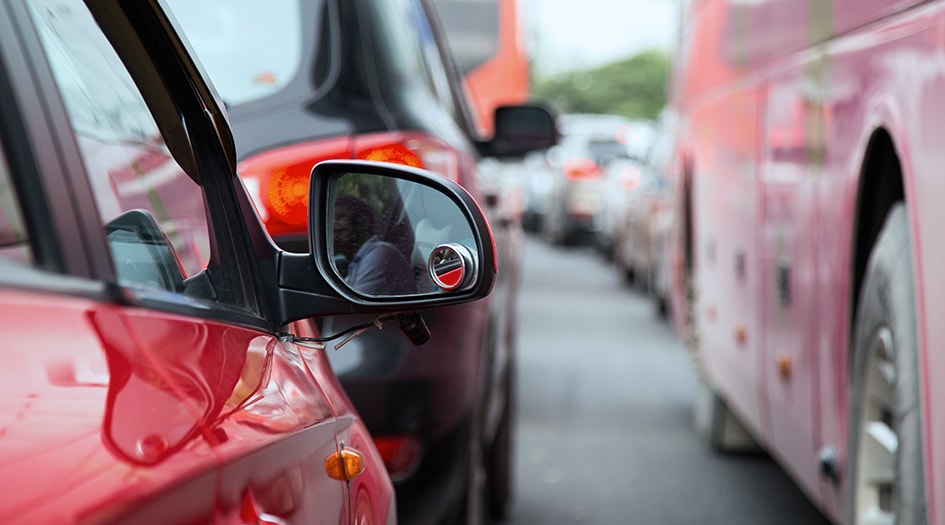 Des voitures bloquées dans la circulation, avec un gros plan sur le rétroviseur d’une voiture rouge, mettant en évidence les mythes sur l’assurance auto.