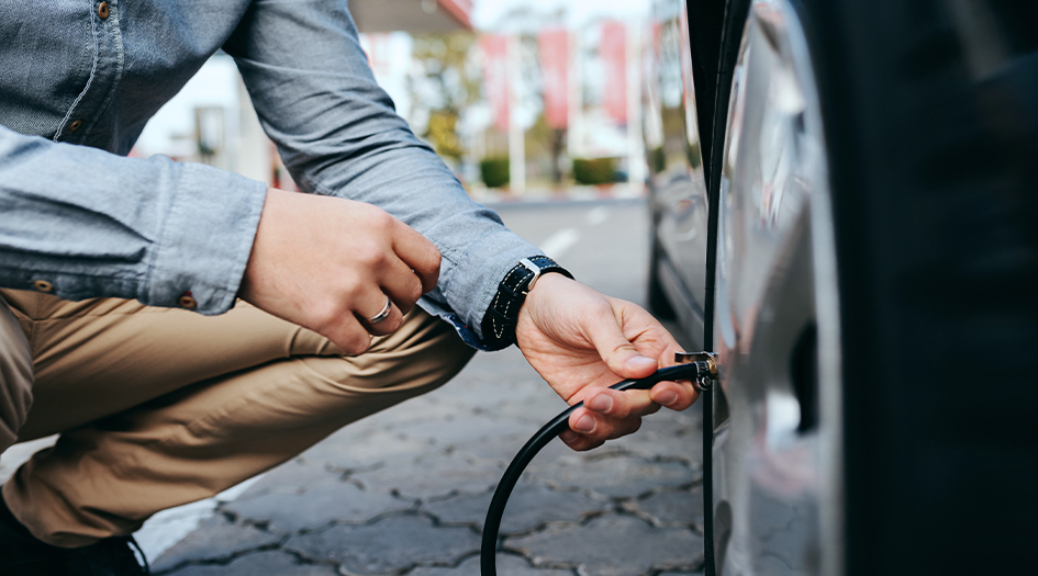 A close up of a man putting air in his car tires shows you how to maintain a vehicle you don't drive often