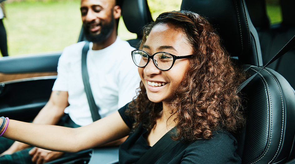 Une jeune femme conduit avec un homme plus vieux, illustrant comment choisir un véhicule approprié pour un adolescent.