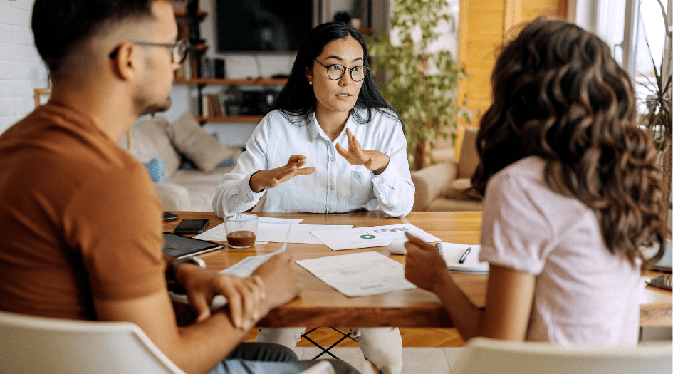 A woman explains how credit score can affect business insurance rates to a man and woman who own a small business.