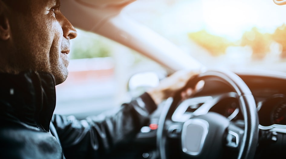 A man looks ahead while driving and considers his options for advanced driver assistance systems