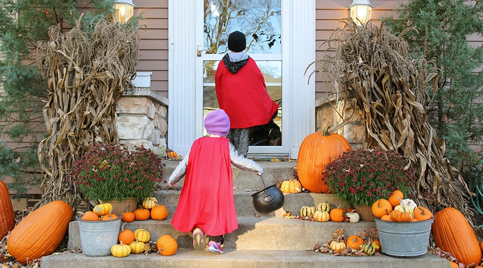 Deux enfants à la porte d’une maison décorée pour l’Halloween, illustrant comment passer l’Halloween en toute sécurité.