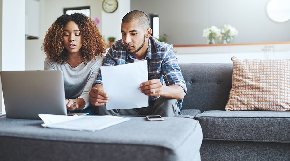 A couple looks at some papers and their laptop as they look for ways to save on home insurance