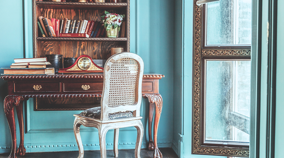 An old chair and desk sits in a blue room, as an example of an antique or family heirloom you need to protect