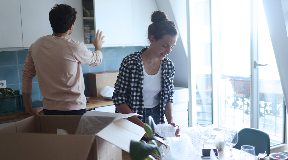 A man and woman unpack boxes in a kitchen, showing what you need to know when buying your first home