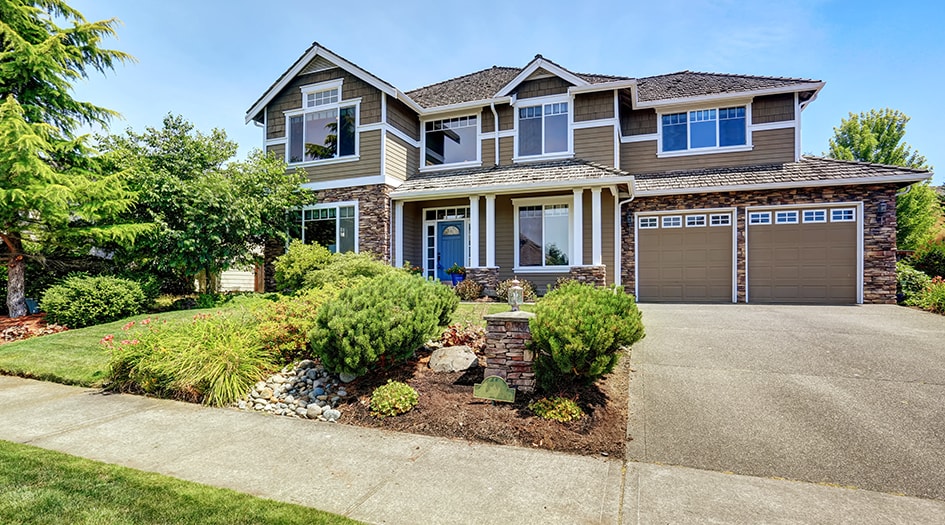 A large brown house with landscaping makes a good first impression, showing you how to improve curb appeal when putting your house on the market