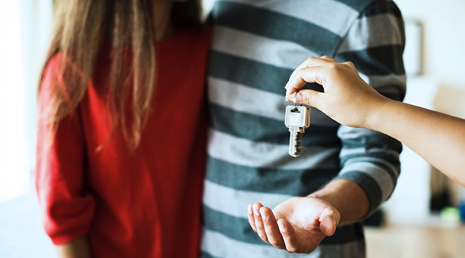 A couple holds out their hands for a set of keys, showing everything you need to know about landlord insurance