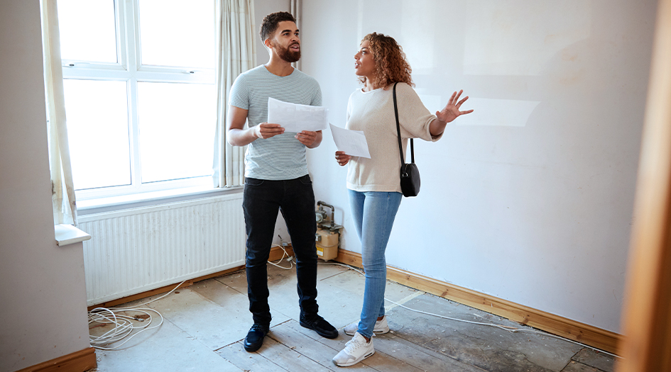 Un homme et une femme sont dans une pièce vide afin d’illustrer quelles questions poser en magasinant une nouvelle maison.