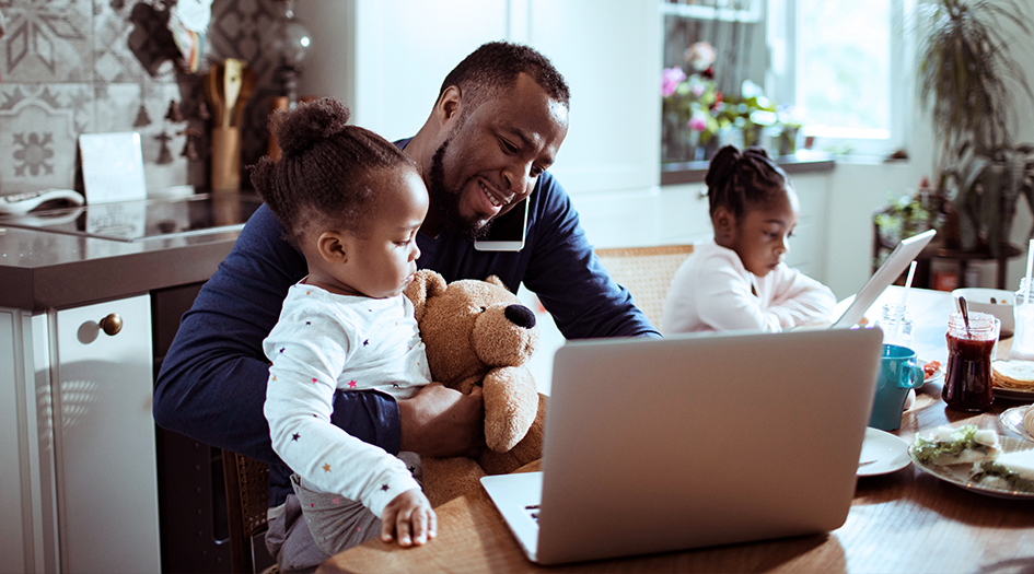 A man sits with his children while talking on the phone and browsing his laptop, as he learns everything about renewing his home insurance policy