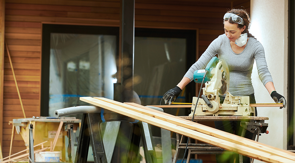 Here are the things to think about when planning a home renovation, as shown by a woman sawing planks of wood