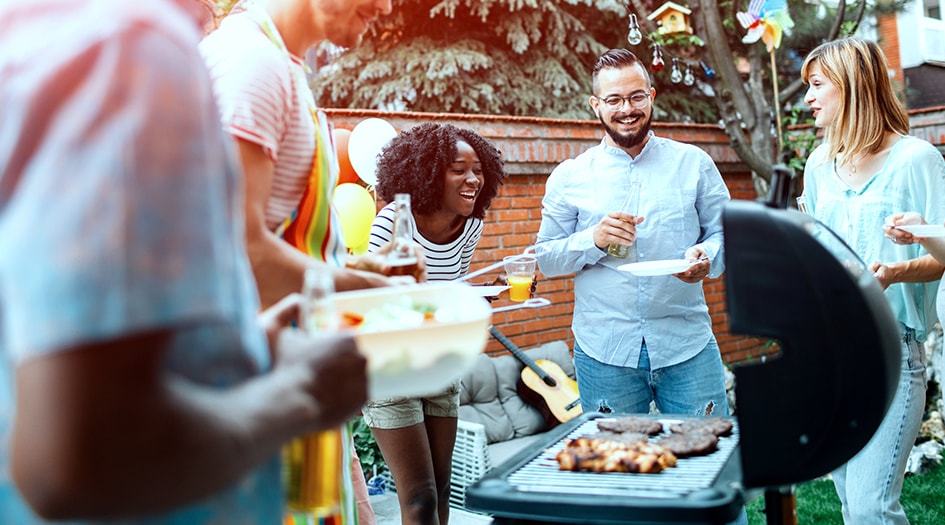 Five people are gathered around a barbecue enjoying some food, showcasing some tips for a chill grilling season