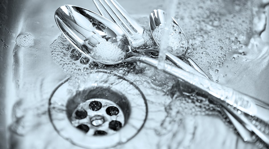 Three kitchen utensils sit in a sink with water, showing you how to prevent a sewer backup