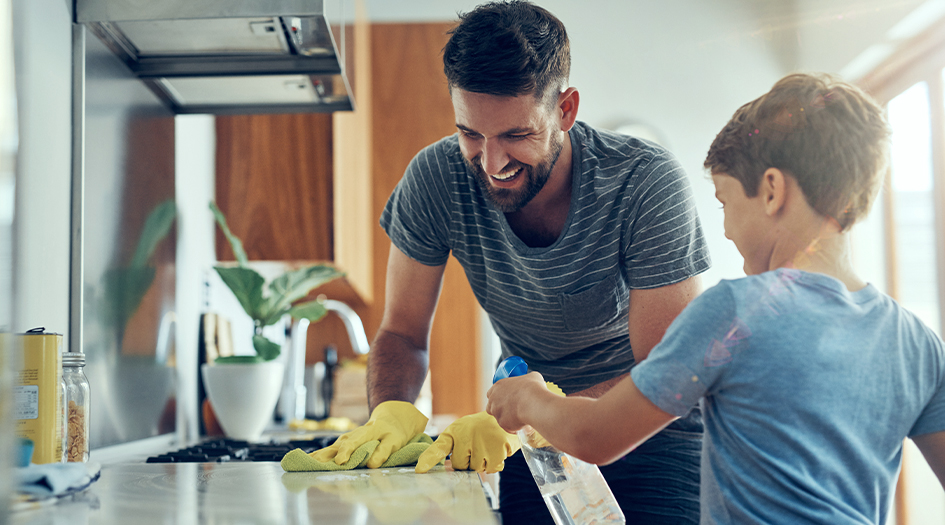 A man and a boy work together to clean the kitchen counter, showing you some tips for successful spring cleaning