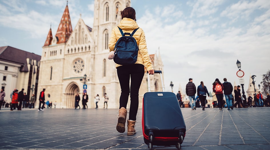 A woman pulls a suitcase outside in front of a church, showing how to protect your stuff while travelling