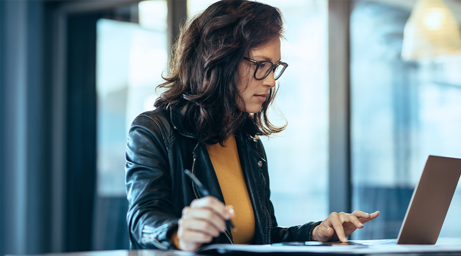 A woman looks at her computer while writing down notes on the home insurance discounts that could lower her premium 