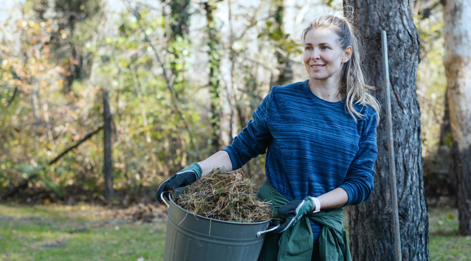 A woman caries a pail of dry grass, showing one way to prevent fires on your property