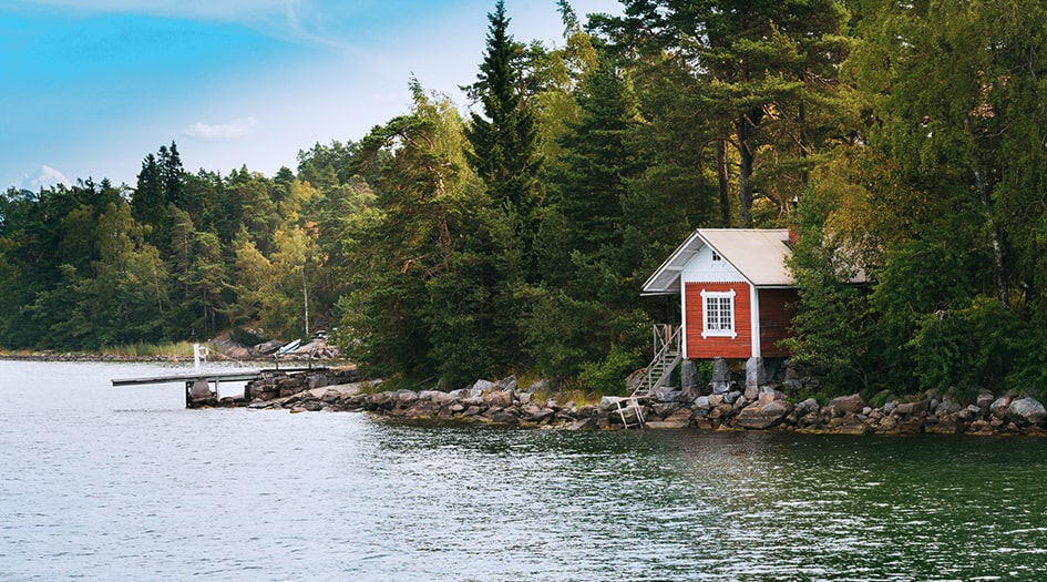 Vous pourriez souscrire une assurance des résidences secondaires, illustrée par ce petit chalet rouge devant un lac.