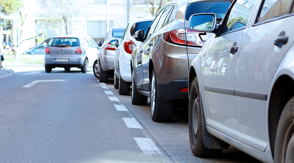 A line of cars parallel parked at the side of the road show some types of vehicles that tend to cost less to insure.