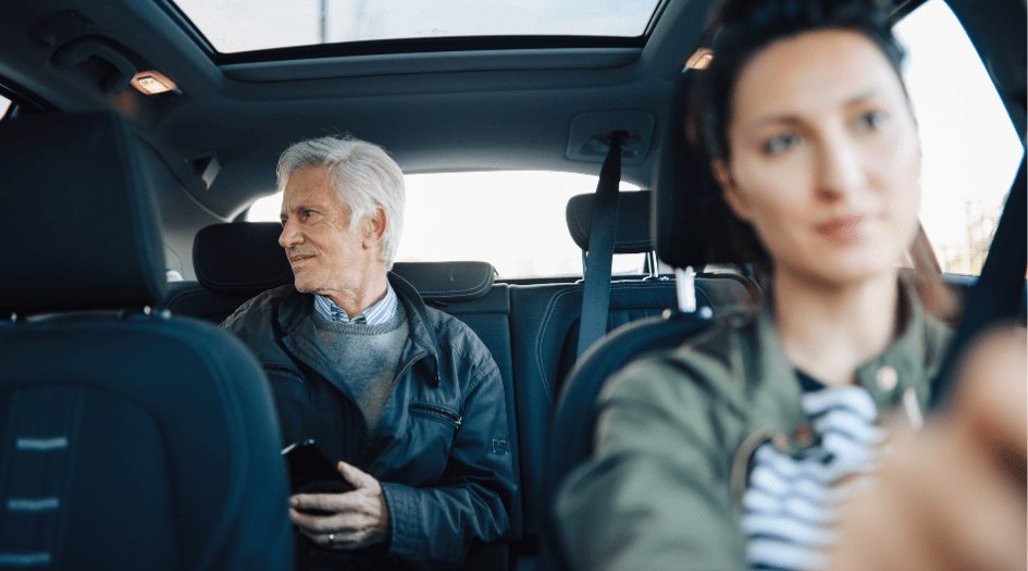 A man sits in a rideshare car, showing one way the transportation replacement endorsement covers you after an accident.