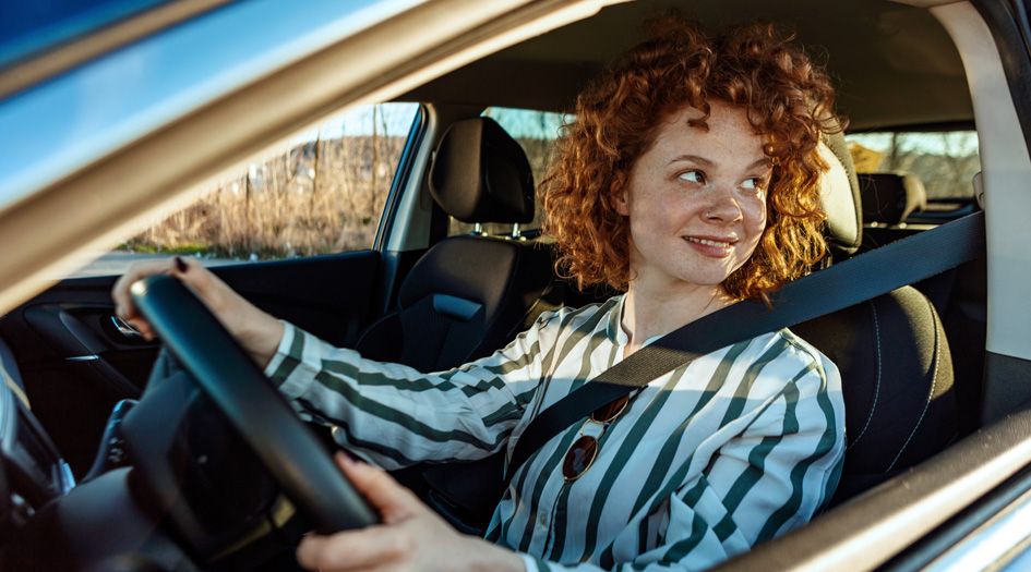 There are questions you should ask before buying a used a used car, as shown by a woman sitting in the driver’s seat of a car looking over her shoulder