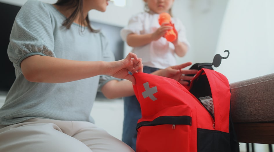 Une femme remplit une trousse de premiers soins, illustrant une façon de se préparer pour une catastrophe naturelle.