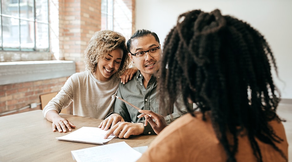 Un homme et une femme examinent un contrat avec une autre femme, montrant pourquoi les propriétaires d’habitations louées devraient tenir compte de ces huit conseils.