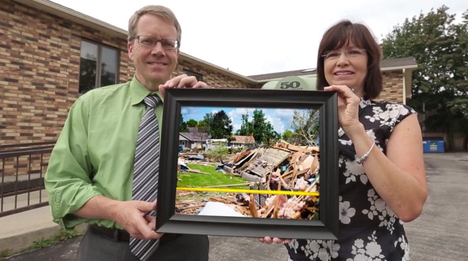 An Economical customer holds up a picture of his storm damaged business