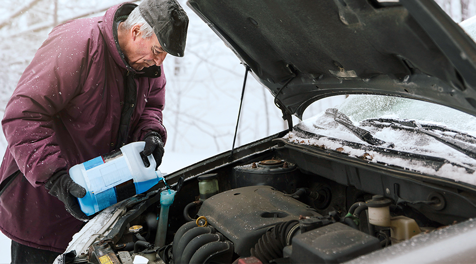 A man fills his car with windshield washer fluid, showing you how to get your car ready for winter