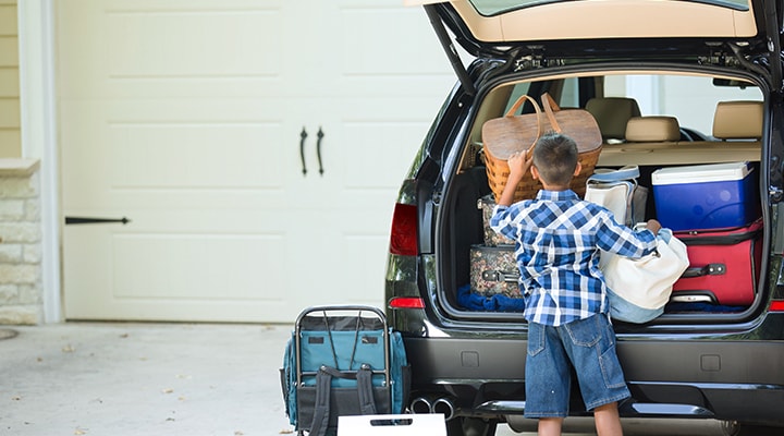A little boy packs the back of an SUV with the must-have items for a safe cottage getaway