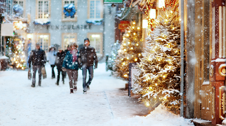 People with shopping bags walk down a shovelled road with storefronts, showing how businesses can get ready for winter