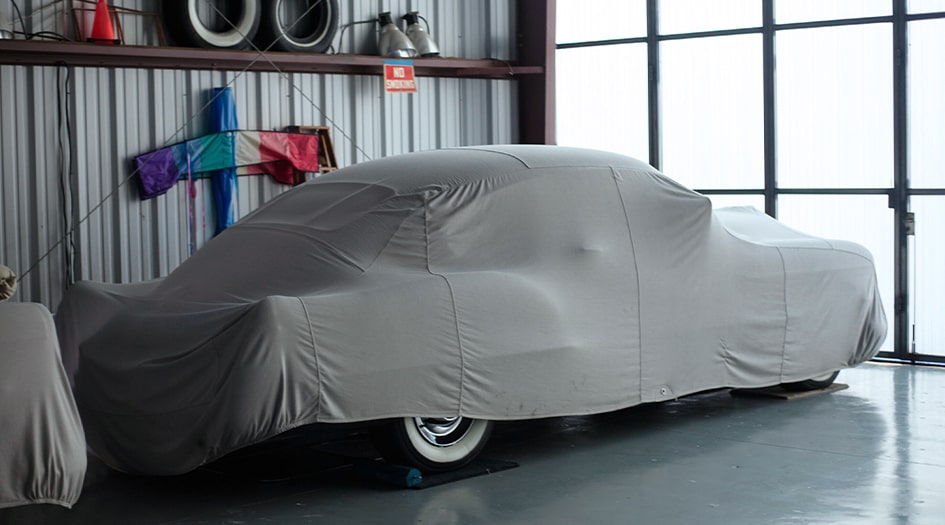 A car is covered by a tarp in a garage, showing you one way to store your car for winter