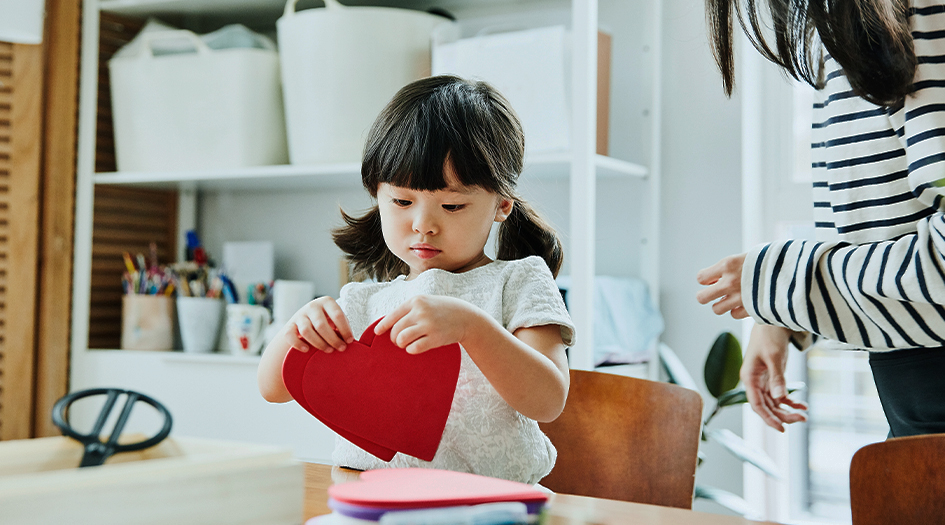 A little girl makes a craft with paper hearts, showing you some simple DIY projects to tackle with materials you have at home