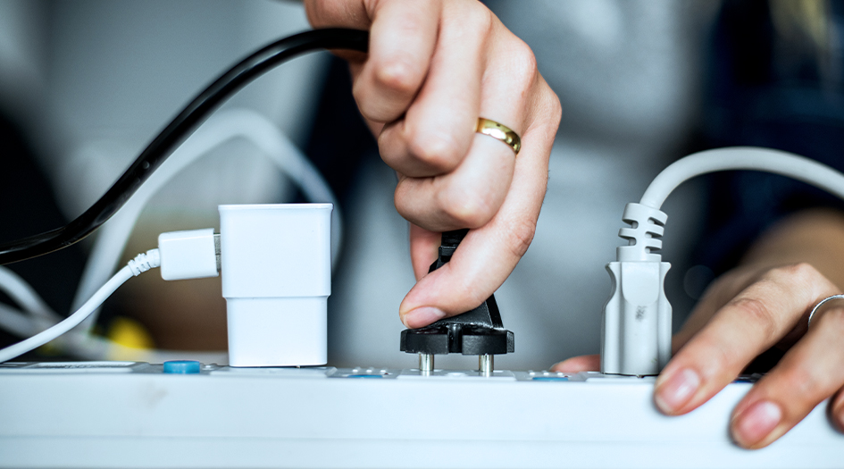 A close up of someone plugging a cord into a power bank, showing you how to prevent electrical fires at home