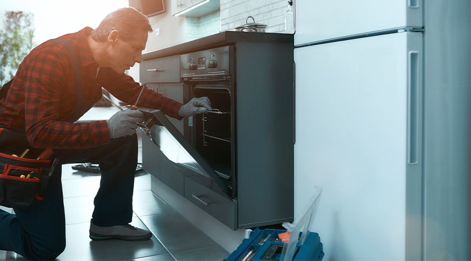 A technician checks inside a kitchen oven, showing you how to detect a natural gas leak in your home