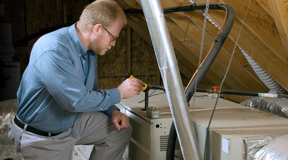 A man shines a flashlight on a furnace, showing you how to get your home ready for spring