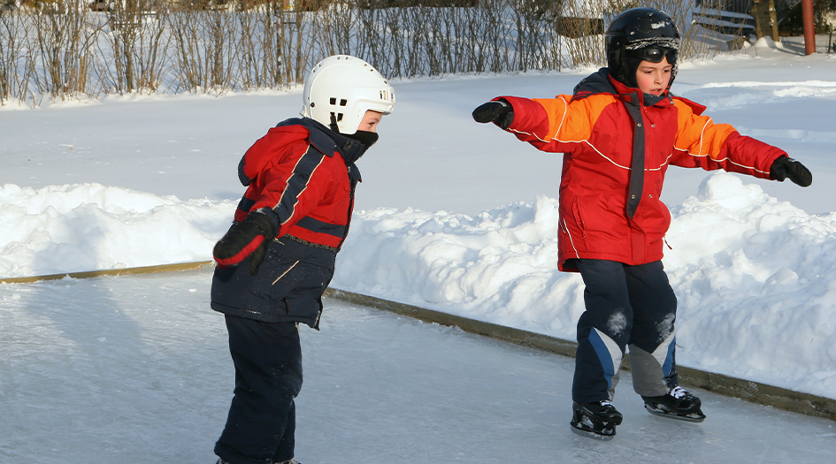 Two kids skate on an outdoor rink, showing how building a skating rink in your backyard can affect your home insurance