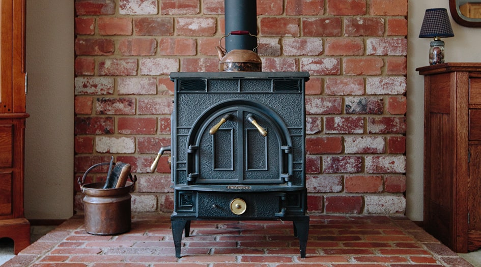 Always follow safety tips for wood stoves and pellet stoves, like this black wood stove standing on a brick platform