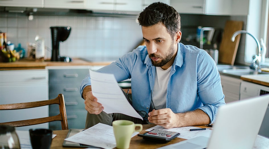 A man reads paperwork at his laptop, as he gets the lowdown on insurance deductibles