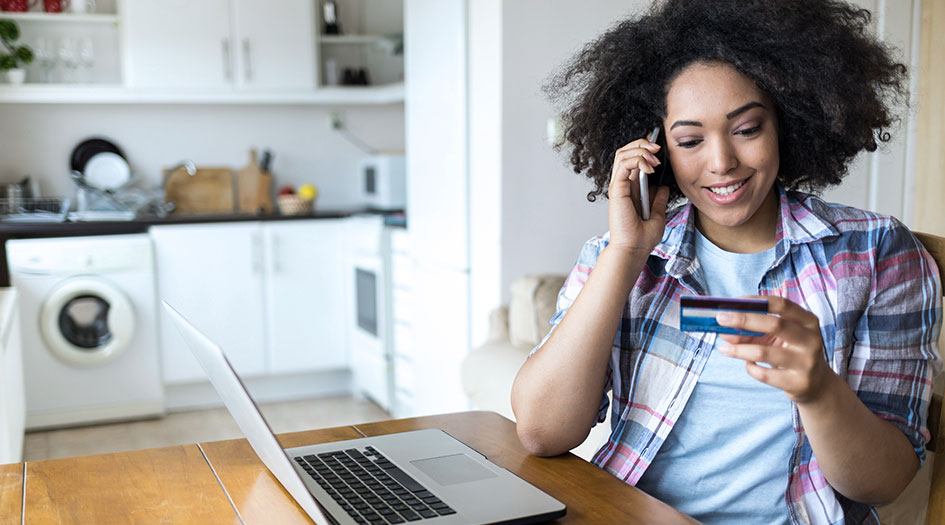 A woman reads off her credit card information while talking on a cellphone, as she makes sure not to miss an insurance payment