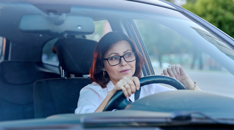 Use defensive driving techniques if someone exhibits road rage, as shown by a woman sitting at the steering wheel in her car.