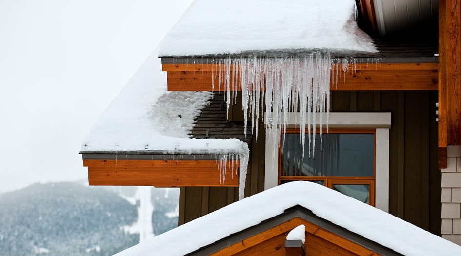 A close up of a house with large icicles hanging off the roof show everything you need to know about ice dams