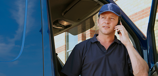 Delivery driver stands outside his van talking on a cell phone
