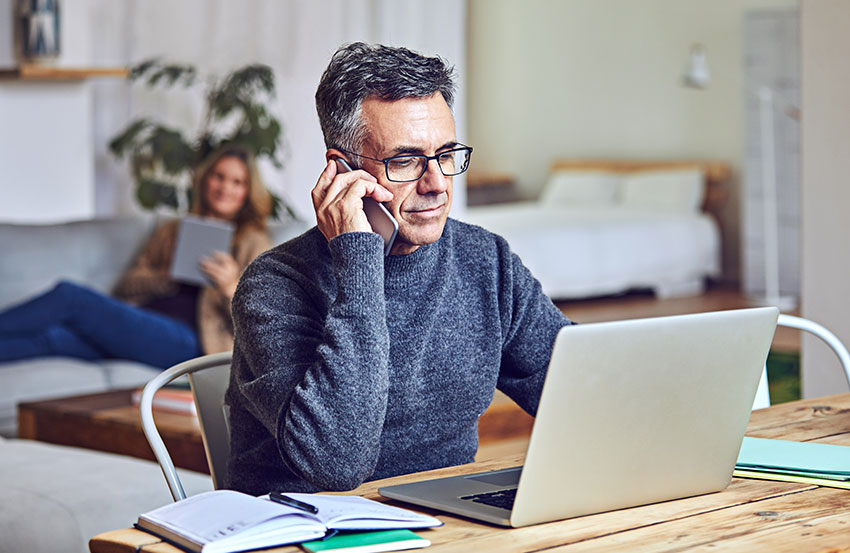 A person working on their laptop computer and talking on their phone